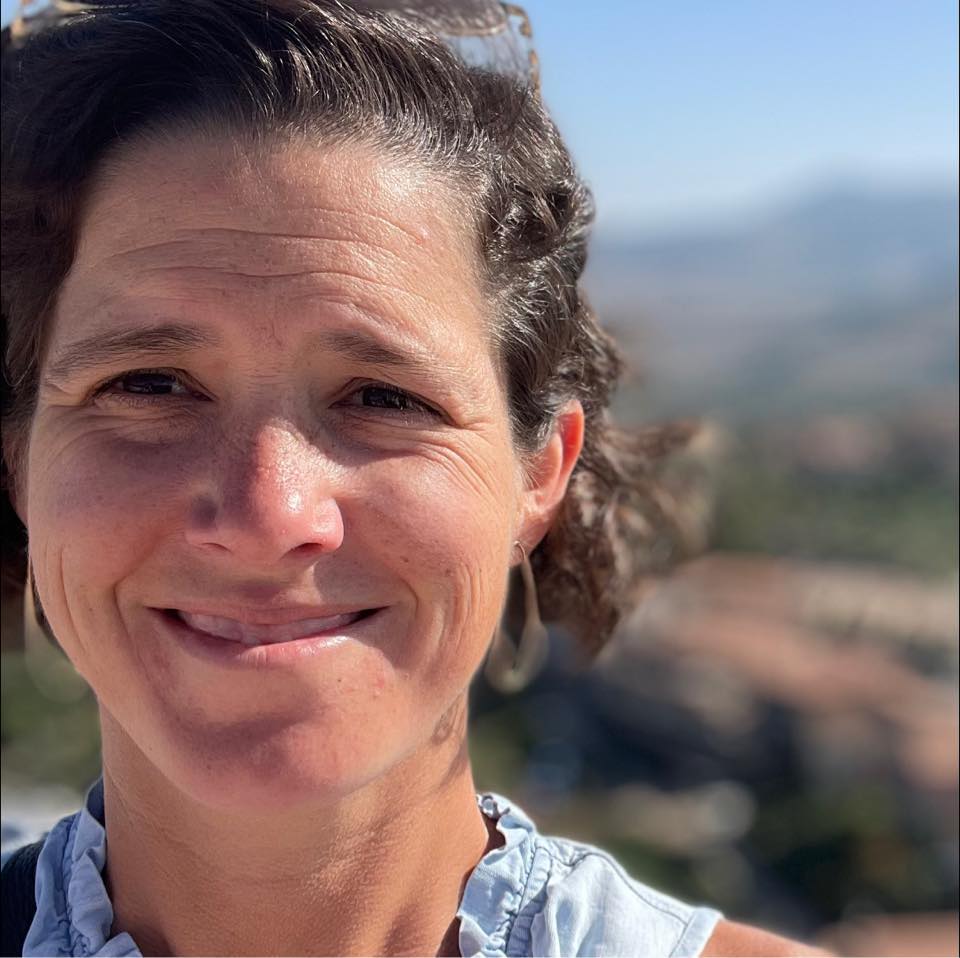 Grace Gamble smiling outdoors on a sunny day with mountains in the distance